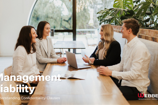 A group of four people, two women and two men, are sitting at a wooden table in a modern office environment. They are engaged in a discussion and smiling. A laptop is open on the table. Text on image reads: "Management Liability: Understanding Confidentiality Clauses for Better Workplace Trust.