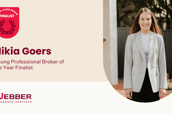 A woman with long hair stands outdoors, smiling, wearing a plaid blazer over a white shirt. The left side of the image shows text that reads, "S&N Young Broker Finalist. Nikia Goers. Young Professional Broker of the Year Finalist," with the Webber Insurance Services logo below.